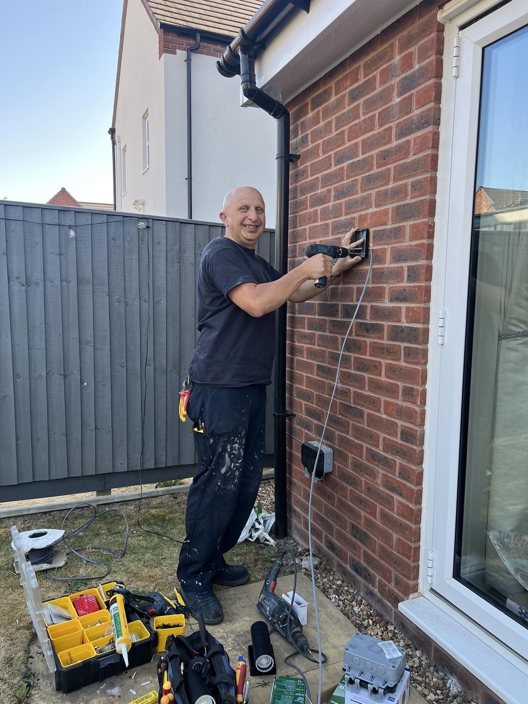Norman fitting an outdoor socket by a patio door
