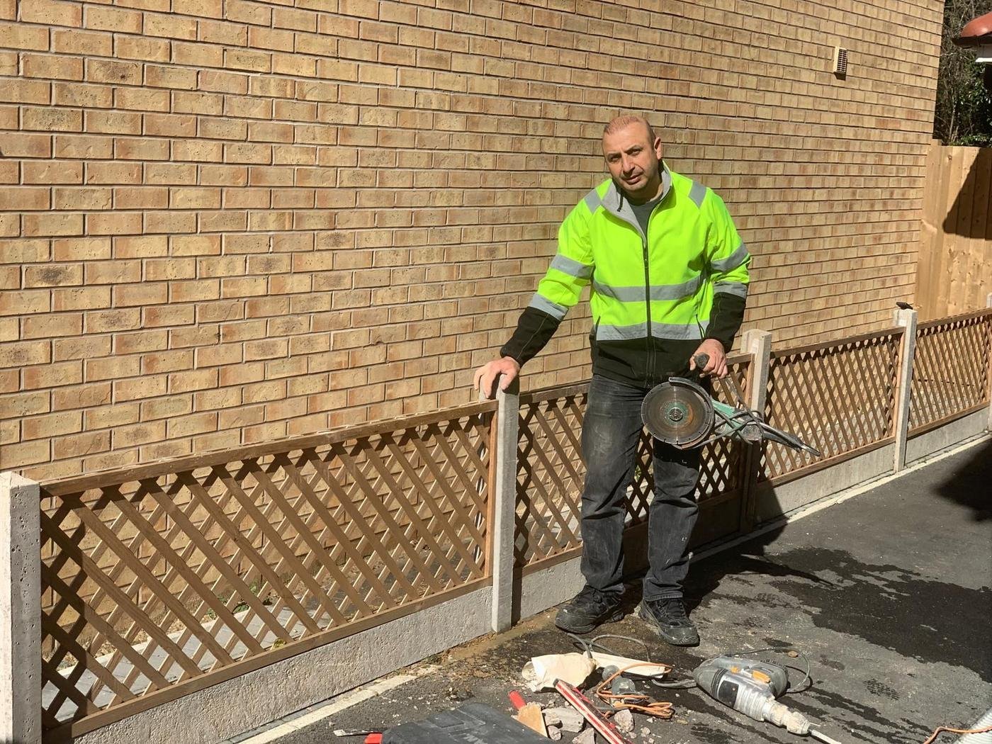 Norman in hi-vis putting up a fence with trellis on top