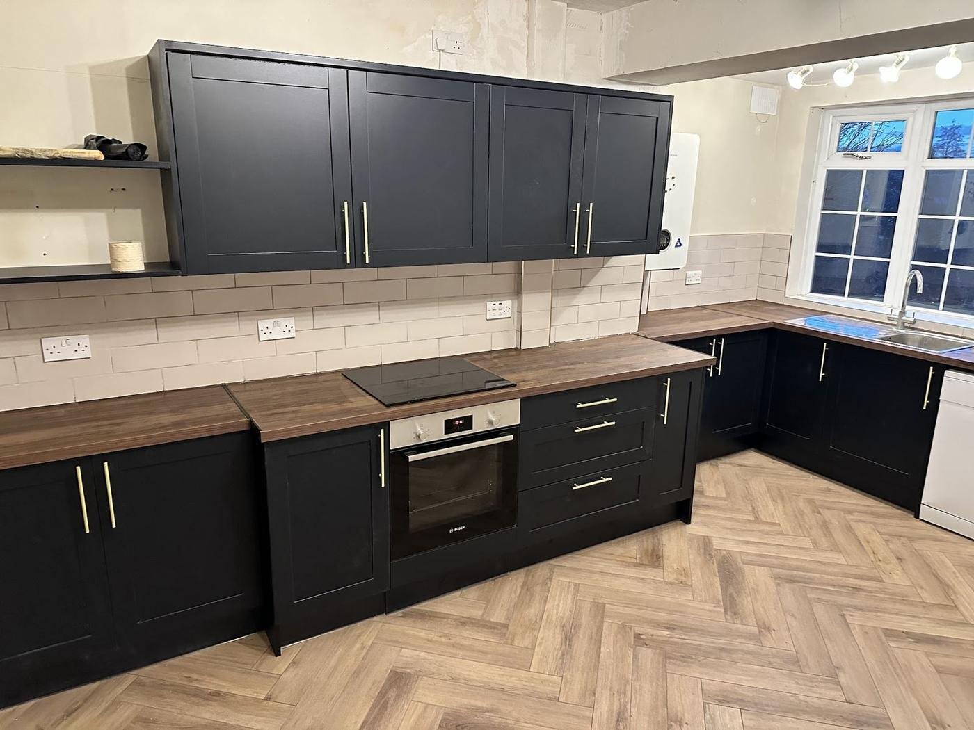 Navy kitchen units with a wood worktop and herringbone floor