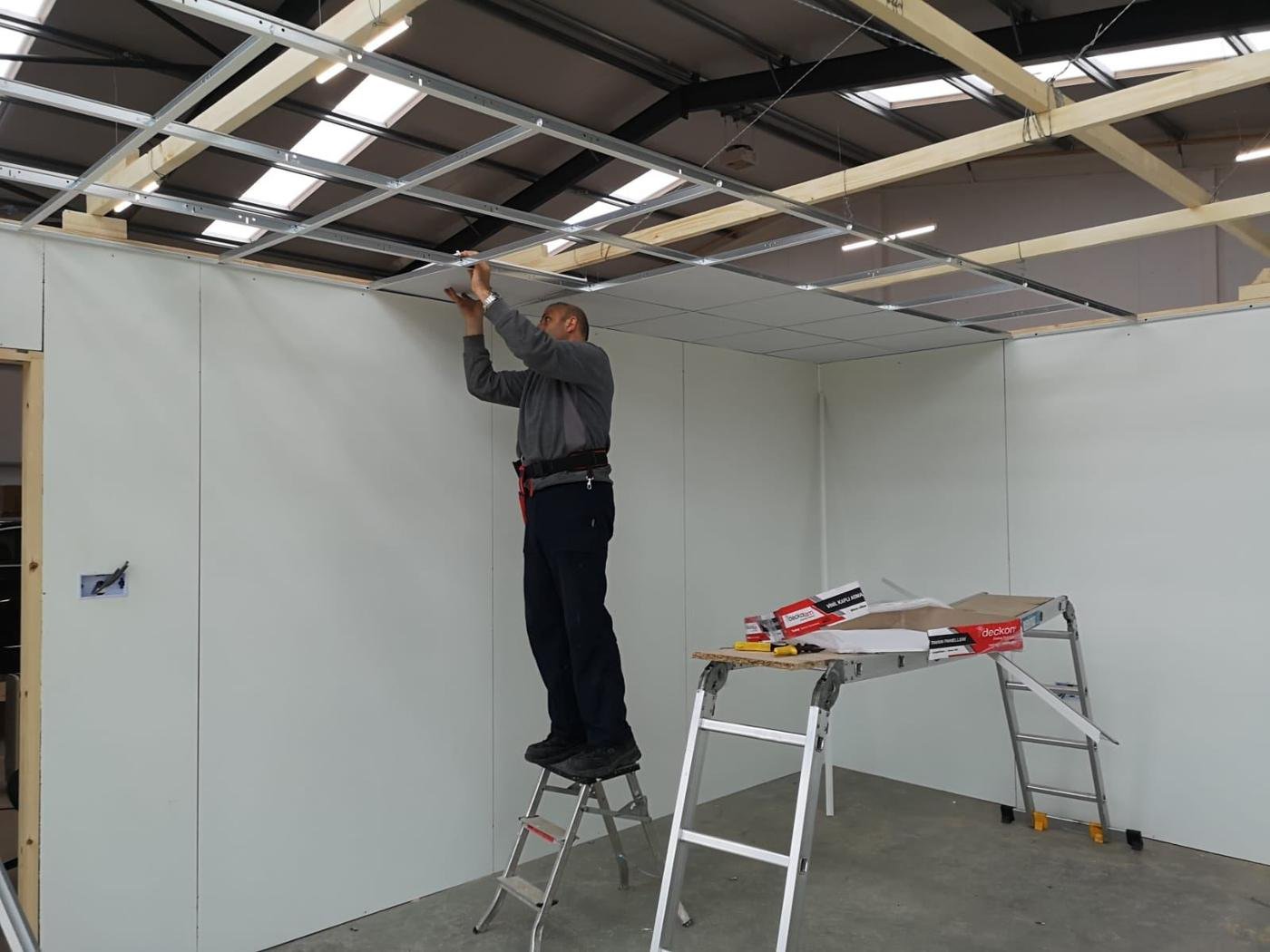 Norman fixing a ceiling grid above new stud walls