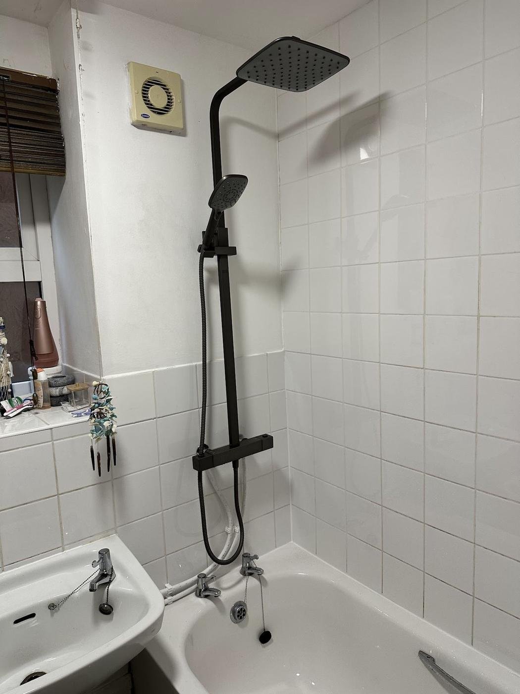 A black thermostatic shower fitted over a white bath